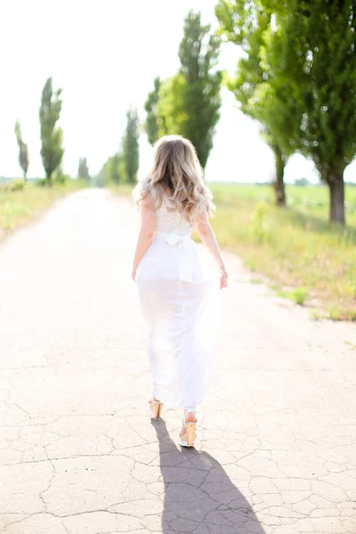 Πίσω όψη της καυκάσιας γυναίκας που φοράει λευκό φόρεμα και περπατάει στο δρόμο. — Φωτογραφία Αρχείου