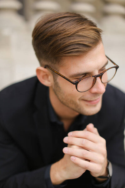 Closeup portrait of european man wearing black suit and glasses.