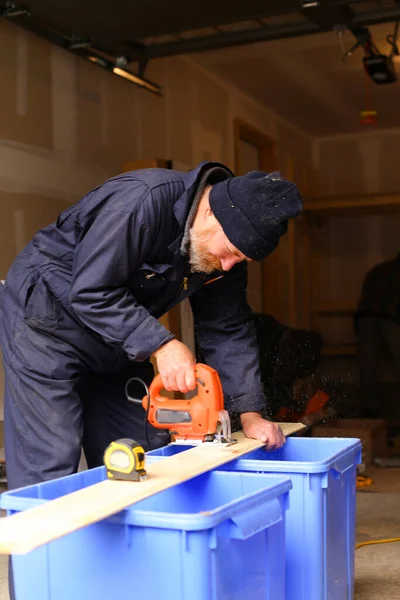 Europäische Handwerker schneiden Holz mit der Stichsäge auf der Baustelle. — Stockfoto