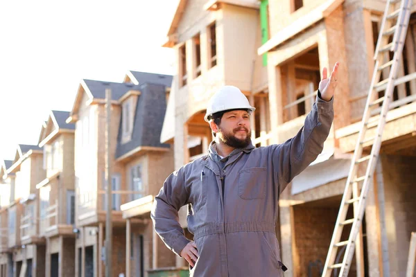 Capataz e arquiteto caucasiano adulto que dá indicação no local de construção e wearinhg hardhat . — Fotografia de Stock