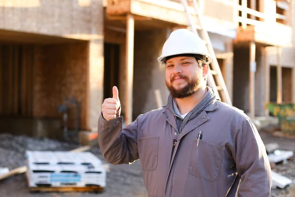 Retrato do capataz vestindo chapéu duro no local da construção e mostrando os polegares para cima . — Fotografia de Stock