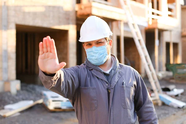 İnşaat alanında maske ve şapka takan beyaz bir ustabaşı..