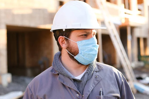 Πορτρέτο του επιστάτη φορώντας μάσκα και hardhat στο εργοτάξιο. — Φωτογραφία Αρχείου