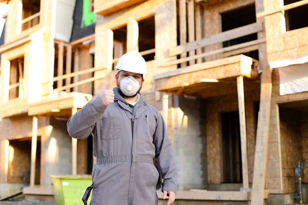 Construction worker wearing respirator near building and showing thumbs up. — Stock Photo, Image