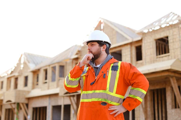 Engenheiro masculino pensando em canteiro de obras com prédio em segundo plano . — Fotografia de Stock