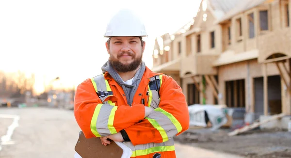 Blanke voorman in oranje werkkleding met notitieboekje op bouwplaats. — Stockfoto