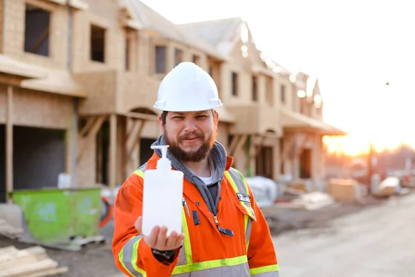 Trabalhador do construtor que dá sabão desinfetante no local de construção . — Fotografia de Stock