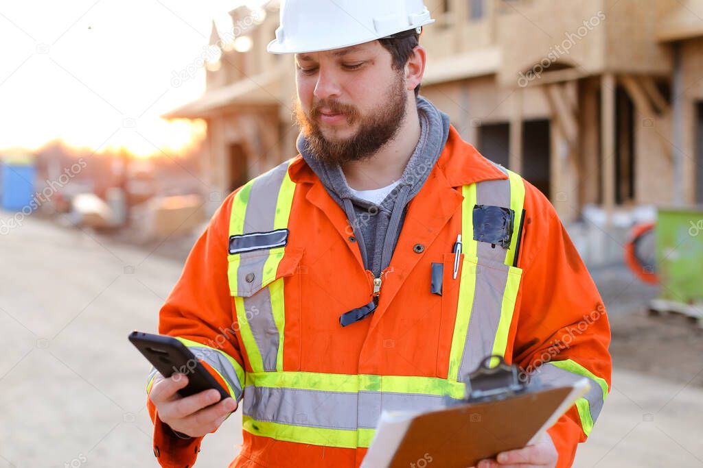 Foreman browsing by smartphone and holding notebook.