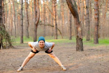 Genç yetişkin bir adam parkta çatlaklar yapıyor, sabah.