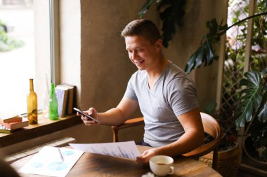 Cafe 'de dokümanlar ve akıllı telefonlarla çalışan Avrupalı bir serbest yazar..