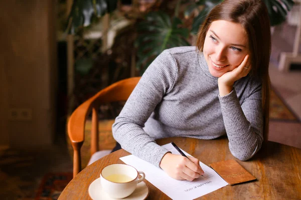 Girl filling visa application, passport and cup on table. — Stock Photo, Image