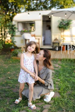 Tekerlekli sandalyede sevimli kızına sarılan genç bir kadın..