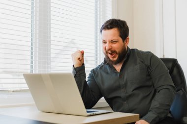 Pencere kenarında dizüstü bilgisayarla ofiste oturan başarılı girişimci.