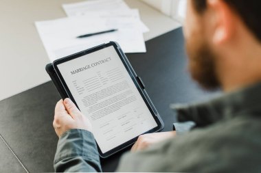 Ofisteki tablette evlilik sözleşmesini okuyan adamı kapat..