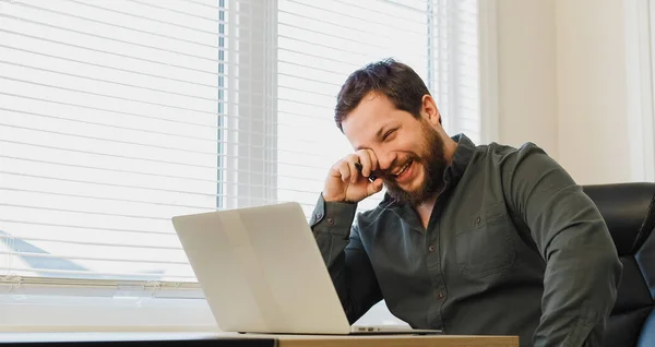 Financiador sorrindo sentado com caneta e laptop no gabinete. — Fotografia de Stock