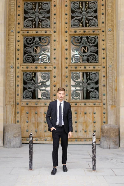 Bello giovane uomo in piedi vicino alla porta di legno. — Foto Stock
