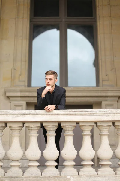 Joven chico guapo apoyado en la barandilla de hormigón balcón en París. — Foto de Stock