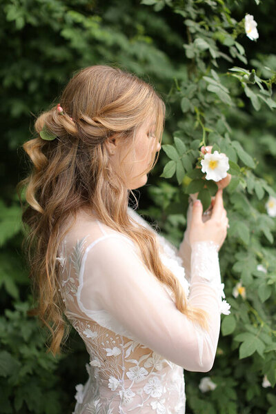 Profile portrait of blonde bride without vail in green plant background.
