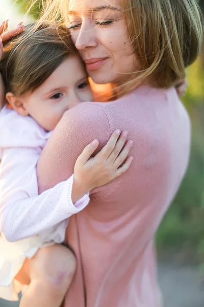 Portret europejskiej matki przytulającej córeczkę i uśmiechającej się. — Zdjęcie stockowe