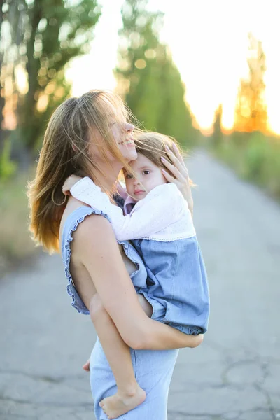 Blonde young european mother holding female kid on road. — Stock Photo, Image