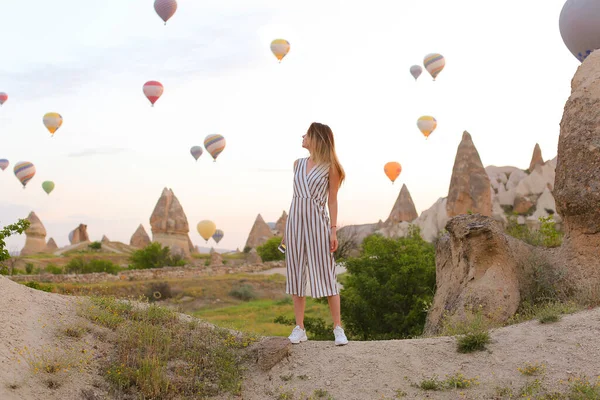 Girl standing with many hot air balloons on background in Capadocia, Turkey. — Stock Photo, Image