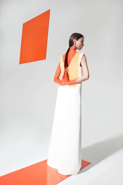 Young stylish female with orange limelight square behind — ストック写真