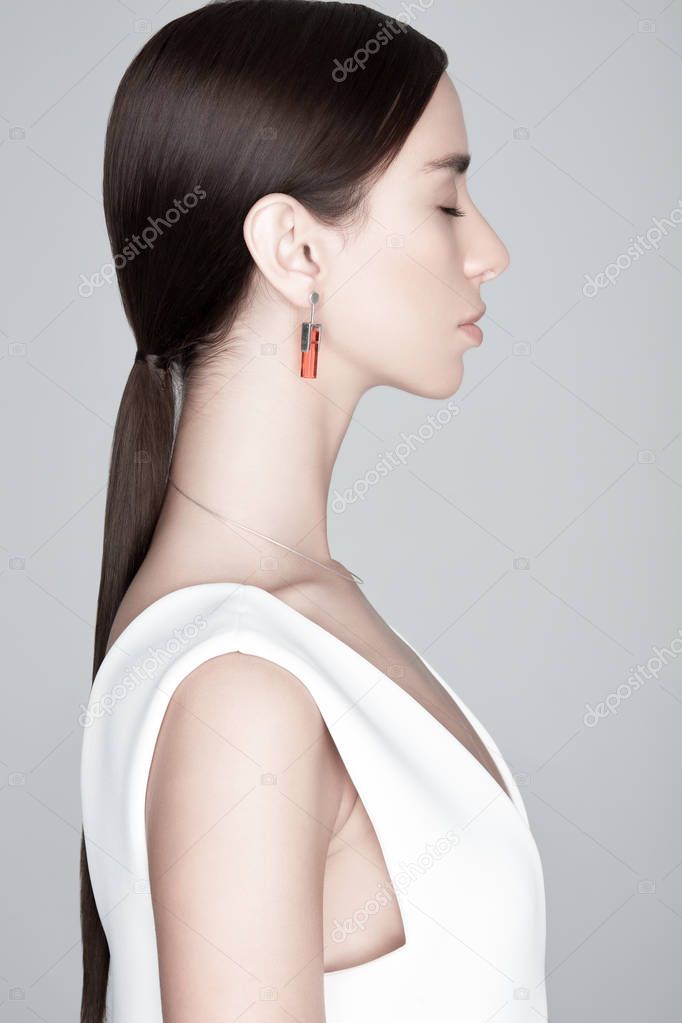 Young trendy female with earring with orange gemstone