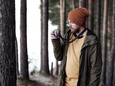 İnce ormanda fotoğraf çeken kameralı adam