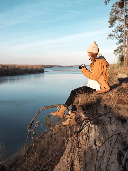 Hiker taking photo while sitting against river