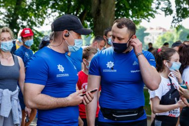 Uzhgorod, Ukrayna - 7 Haziran 2020: Sağlık maskeli polis memurları, Ukrayna 'daki karantinanın zayıflaması sırasında düzenlenen etkinlik başlamadan önce konuşuyor. Koşu yarışına katılanlar 10 km koştu.