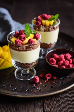 Katmanlı mango tatlı krem peynir, ezilmiş bisküvi ve cam kavanozlarda hizmet freeze kurutulmuş frambuaz