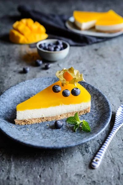 Homemade no bake mango cheesecake decorated with blueberries and physalis