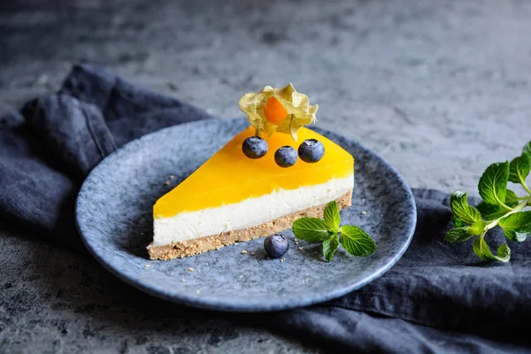 Homemade no bake mango cheesecake decorated with blueberries and physalis