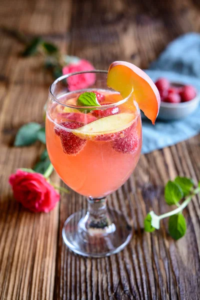 Delicious raspberry peach mimosa drink on a wooden background