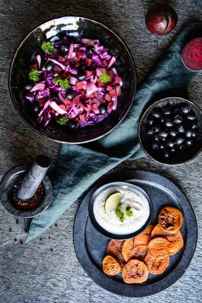 Felii de cartofi dulci prăjiți servite cu smântână, măsline negre și salată — Fotografie, imagine de stoc