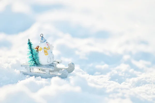 雪人坐在雪橇上 雪堆里有一棵圣诞树 冬季背景 — 图库照片