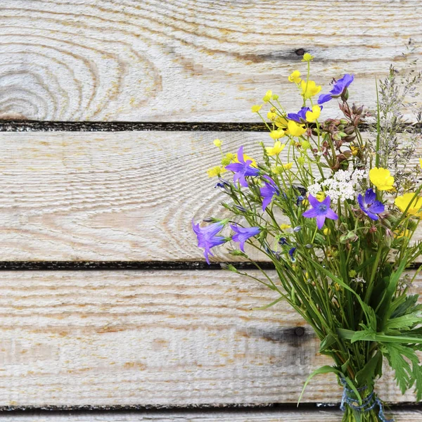 Bouquet of field flowers on a wooden background.