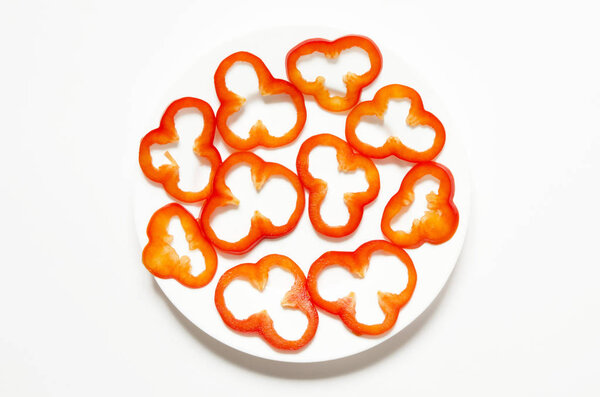 Top view of sliced red bell pepper  in a white plate on white counter top. - Image