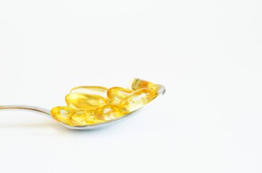  Beyaz arka plan üzerinde gümüş kaşık Omega 3 balık yağı kapsülleri. Sağlık kavramı. Kopyalama alanı.