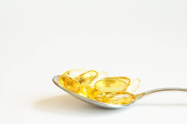  Beyaz arka plan üzerinde gümüş kaşık Omega 3 balık yağı kapsülleri. Sağlık kavramı. Kopyalama alanı.
