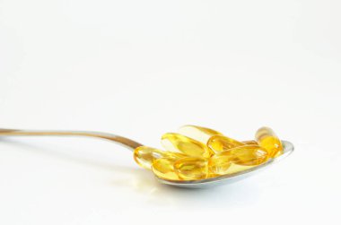  Beyaz arka plan üzerinde gümüş kaşık Omega 3 balık yağı kapsülleri. Sağlık kavramı. Kopyalama alanı.
