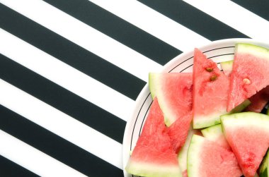 Çizgili arka planda tabakta taze kırmızı karpuz dilimi. Yaz konsepti. Üstte, Düz yatıyordu. - Resim 