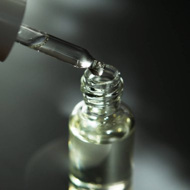 Pipet ile kozmetik veya tıbbi cam şişe. Cilt Bakımı kavramı. Doğal sert ışık, derin gölgeler. -Görüntü