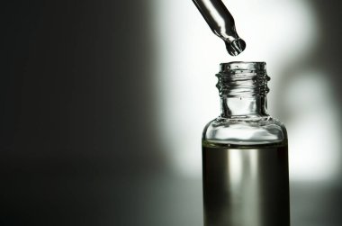 Pipet ile kozmetik veya tıbbi cam şişe. Cilt Bakımı kavramı. Doğal sert ışık, derin gölgeler. -Görüntü