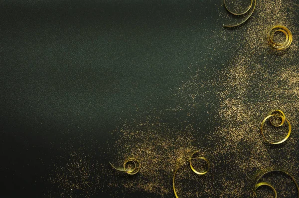 Golden sparkles and ribbons on black background. Festive concept. - Image