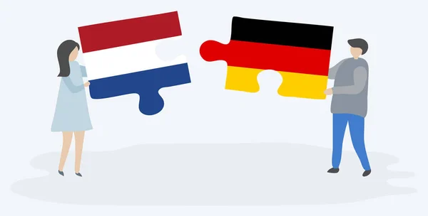 オランダとドイツの旗を持つ2つのパズルのピースを保持しているカップル オランダとドイツの国のシンボル — ストックベクタ