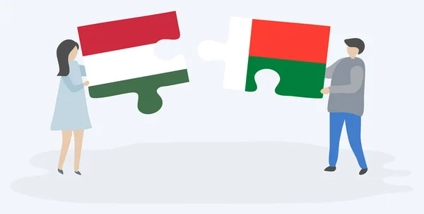 ハンガリーとマダガスカルの旗を持つ2つのパズルピースを保持しているカップル ハンガリーとマダガスカルの国のシンボル — ストックベクタ