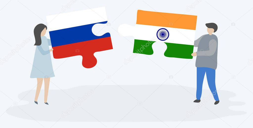 Couple holding two puzzles pieces with Russian and Indian flags. Russia and India national symbols together.