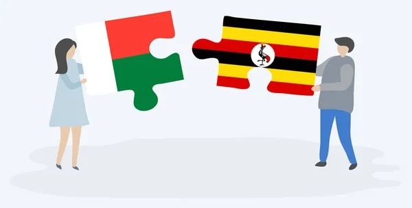 Para Trzyma Dwa Kawałki Puzzli Madagaskaru Ugandy Flagi Madagaskar Uganda — Wektor stockowy