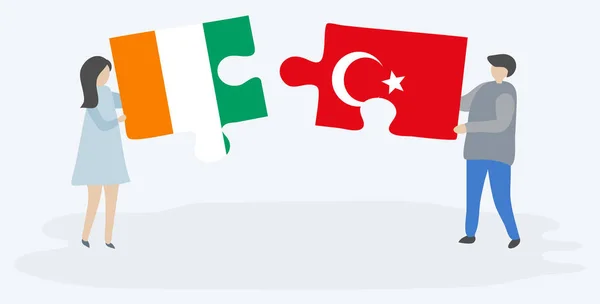 一对夫妇拿着两块拼图 上面挂着科特迪瓦和土耳其国旗 象牙海岸和土耳其国家符号在一起 — 图库矢量图片